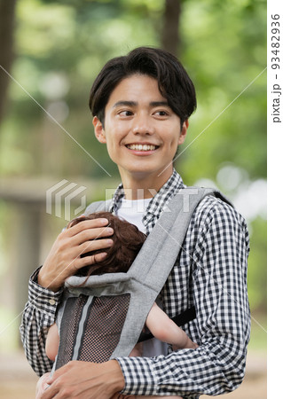 抱っこ紐で赤ちゃんを抱っこする若い父親 抱っこ紐で赤ちゃんを抱っこする若い父親 93482936