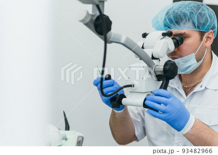 Doctor used microscope. Dentist is treating patient in modern dental office. Operation is carried out using cofferdam. Client is inserted and restored teeth, make denture. Doctor used microscope. Dentist is treating patient in modern dental office. Operation is carried out using cofferdam. Client is inserted and restored teeth, make denture. 93482966