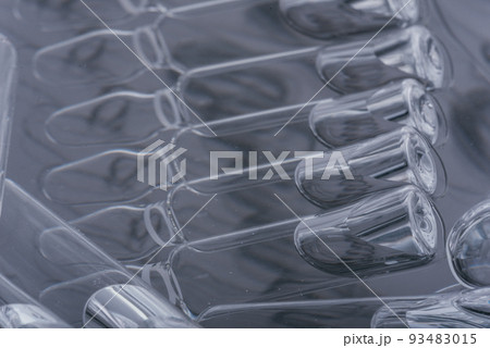 Glass medical ampoule vial for injection. Medicine is liquid sodium chloride with of aqueous solution in ampulla. Close up. Bottles ampule multicolor. Glass medical ampoule vial for injection. Medicine is liquid sodium chloride with of aqueous solution in ampulla. Close up. Bottles ampule multicolor. 93483015