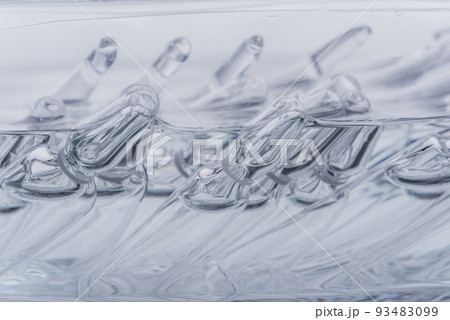 Glass medical ampoule vial for injection. Medicine is liquid sodium chloride with of aqueous solution in ampulla. Close up. Bottles ampule multicolor. 93483099