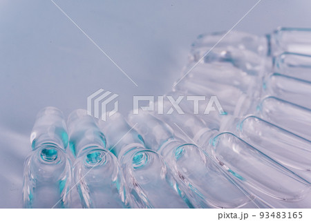 Glass medical ampoule vial for injection. Medicine is liquid sodium chloride with of aqueous solution in ampulla. Close up. Bottles ampule multicolor. Glass medical ampoule vial for injection. Medicine is liquid sodium chloride with of aqueous solution in ampulla. Close up. Bottles ampule multicolor. 93483165