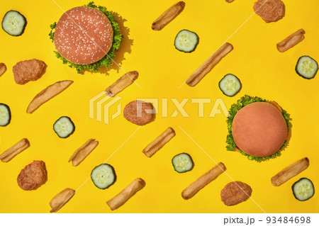 Most popular fast food meal. Chicken nuggets, burgers and french fries on yellow background top view Most popular fast food meal. Chicken nuggets, burgers and french fries on yellow background top view 93484698
