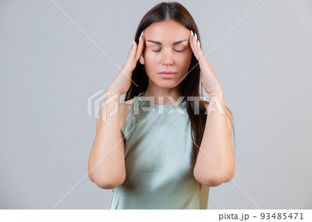 Young beautiful woman has headache, isolated on gray background. Exhausted girl portrait Young beautiful woman has headache, isolated on gray background. Exhausted girl portrait 93485471