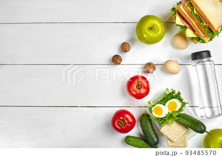 Lunch. Sandwich and fresh vegetables, bottle of water, nuts and fruits on white wooden background. Healthy eating concept. Top view with copy space Lunch. Sandwich and fresh vegetables, bottle of water, nuts and fruits on white wooden background. Healthy eating concept. Top view with copy space 93485570