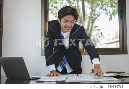 Young Asian businessman financial market analyst sits at their desks and calculate financial graphs showing the results of their investments planning the process of successful business growth 93487314