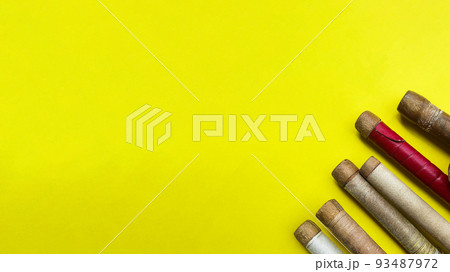 Brown wooden cricket handles which are bound by cotton yarn and artificial leather on yellow background 93487972