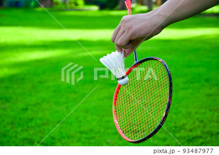 Shuttlecock holding by hand in front of the racket and ready to be served 93487977