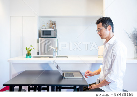 ダイニングキッチンでパソコン作業をする男性 93488169