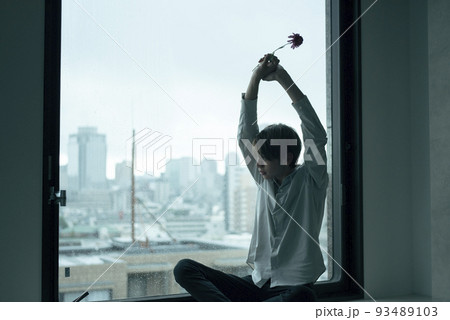 雨の日に窓辺でくつろぐ男性 93489103