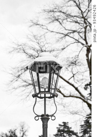 Retro classic snow-covered street light with modern electric balb in calm park 93492426