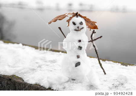 Creative snowman granny or grandpa stone eyes and buttons with sticknear river 93492428