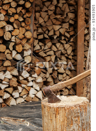 The AX sticks out in the stump. In the background, beautifully stacked firewood for kindling the stove 93493905
