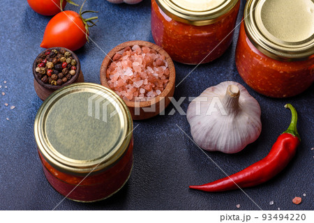 Homemade hot tomato sauce adjika in jars. Tomatoes, chilli pepper, garlic and herbs Homemade hot tomato sauce adjika in jars. Tomatoes, chilli pepper, garlic and herbs 93494220