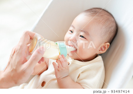 幸せそうにミルクを飲む笑顔の赤ちゃん 93497414