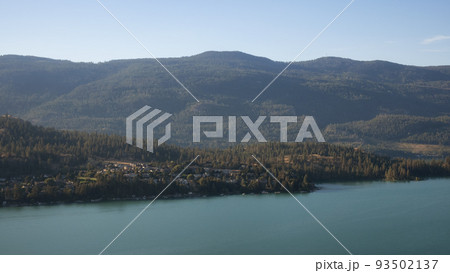 Scenic View of Kalamalka Lake and a small City during sunny summer sunrise. Scenic View of Kalamalka Lake and a small City during sunny summer sunrise. 93502137