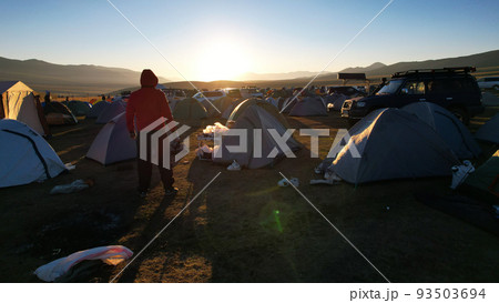 A guy at dawn looks at a camp covered in garbage 93503694
