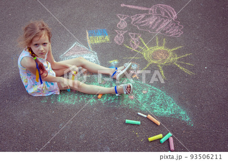 Child from Ukraine draws with chalk. 93506211