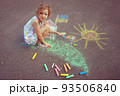Child from Ukraine draws with chalk. 93506840