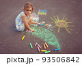 Child from Ukraine draws with chalk. 93506842