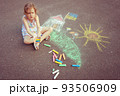 Child from Ukraine draws with chalk. 93506909