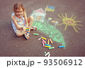 Child from Ukraine draws with chalk. 93506912