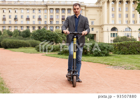 middle-aged white man in business suit rents kicksharing scooter on city street, concept of sustainable lifestyle 93507880