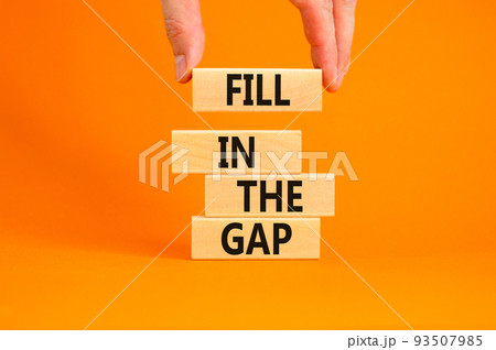 Fill in the gap symbol. Concept words Fill in the gap on wooden blocks on a beautiful orange table orange background. Businessman hand. Business, motivational and fill in the gap concept. 93507985