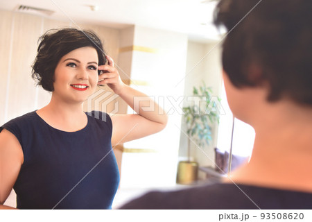 Happy Morning. An attractive young full body woman looks at herself in the mirror in her apartment. Happy Morning. An attractive young full body woman looks at herself in the mirror in her apartment. 93508620