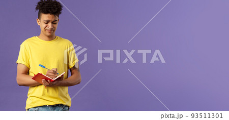 Portrait of unamused, displeased and bothered young man having troubles with homework, smirk and grimacing, trying solve math equation, writing down in notebook, fill-in schedule Portrait of unamused, displeased and bothered young man having troubles with homework, smirk and grimacing, trying solve math equation, writing down in notebook, fill-in schedule 93511301