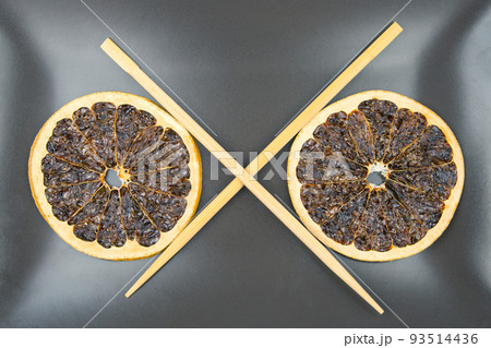 bamboo chopsticks lie on a ceramic plate with dried citrus fruits. items for food 93514436