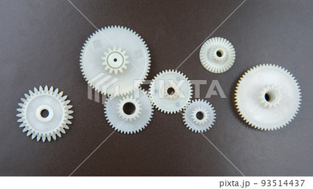 white plastic gears on a dark background. connection mechanism details. subject of movement white plastic gears on a dark background. connection mechanism details. subject of movement 93514437