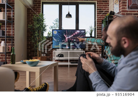 Diverse group of men playing online video games on tv console, gaming competition with controller. Friends having fun with game play on television, celebrating friendship event. Diverse group of men playing online video games on tv console, gaming competition with controller. Friends having fun with game play on television, celebrating friendship event. 93516904
