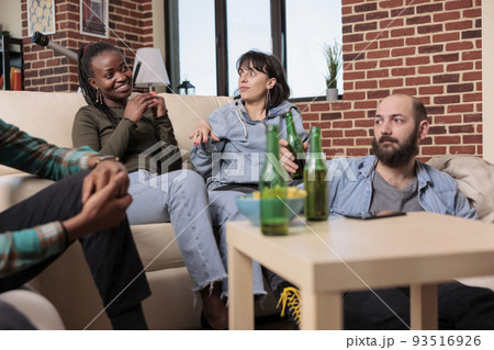 Diverse group of friends laughing and having conversation at fun gathering, drinking bottles of beer. People bonding and talking about leisure activity, enjoying friendship event. Diverse group of friends laughing and having conversation at fun gathering, drinking bottles of beer. People bonding and talking about leisure activity, enjoying friendship event. 93516926