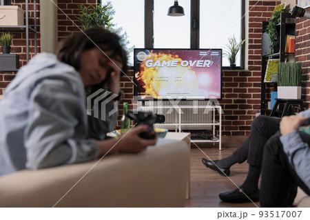 Competitive woman losing after playing shooter video games, feeling frustrated about lost competition. Sad angry person using gaming console to play shooting game, strategy lose. Competitive woman losing after playing shooter video games, feeling frustrated about lost competition. Sad angry person using gaming console to play shooting game, strategy lose. 93517007
