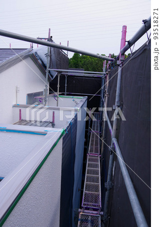 戸建て住宅の外壁塗装　屋根塗装　現場　足場の組まれた家　塗装工事　足場　住宅工事の様子　養生 93518271