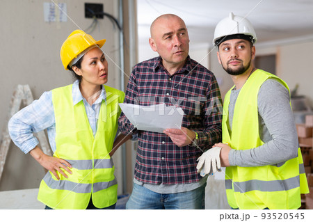 Homeowner discussing home renovation work plan with builders Homeowner discussing home renovation work plan with builders 93520545