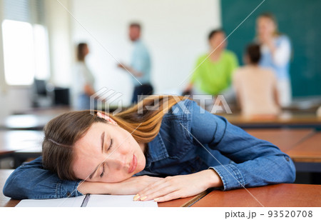 Woman university student sitting at table and sleeping Woman university student sitting at table and sleeping 93520708