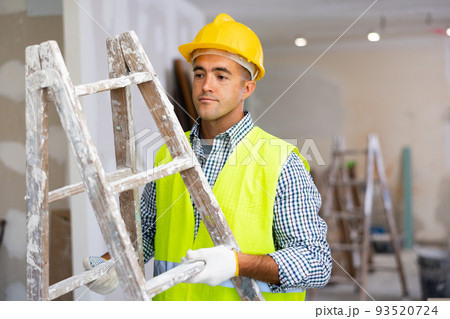 Young foreman carries a stepladder Young foreman carries a stepladder 93520724
