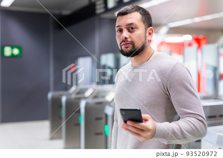 Guy traveler standing on subway station with phone in hands 93520972