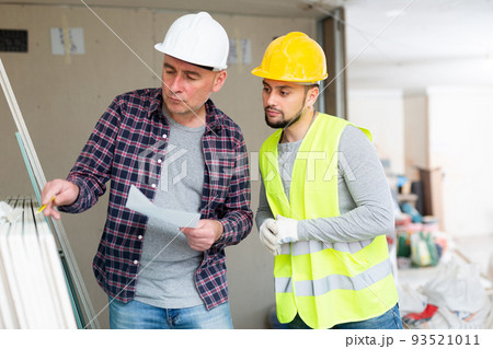 Architect discussing workflow with builder at construction site indoors Architect discussing workflow with builder at construction site indoors 93521011