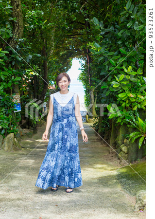 樹齢数百年のフクギの木が並ぶ砂の道を歩く旅ガール、沖縄のパワースポット「フクギ並木」 93523261