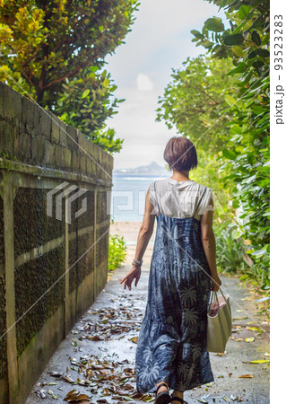 樹齢数百年のフクギの木が並ぶ砂の道を歩く旅ガール、沖縄のパワースポット「フクギ並木」 93523283