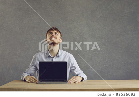 European cheerful man shows a laptop with a black screen on the table 93526092