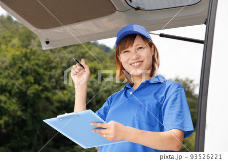 軽貨物自動車のドライバーの女性がバインダーと筆記用具を持っている。引越し業者や配送の仕事をしているイ 93526221