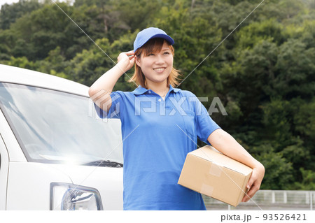軽貨物自動車のドライバー。青いポロシャツと帽子を着て段ボールを運んでいる女性。 93526421