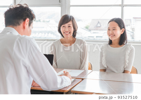 教室で三者面談をする担任の先生と親子（進路相談） 93527510