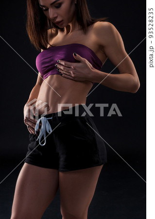 cropped close up body of fit woman wearing shorts and sport top showing slim beautiful stomach and abs in diet fitness and healthy lifestyle concept isolated on black background cropped close up body of fit woman wearing shorts and sport top showing slim beautiful stomach and abs in diet fitness and healthy lifestyle concept isolated on black background 93528235