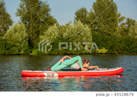 Woman practicing yoga on the paddle board in the morning 93528679