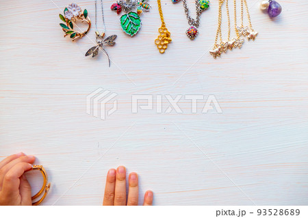 childrens hands play with light summer bijouterie, on white background. concept of womens happines. Copy space 93528689
