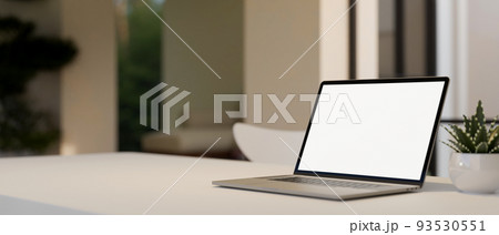 Notebook laptop white screen mockup is on white tabletop over blurred living room background Notebook laptop white screen mockup is on white tabletop over blurred living room background 93530551